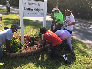 People filling in a flower bed around the Griffin Heights sign