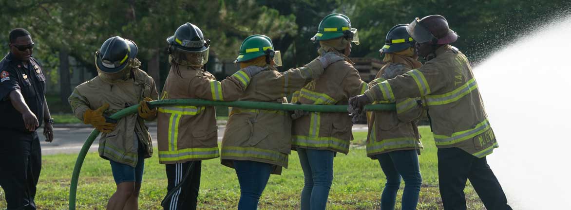 Firefighter teaching civilians how to use hose