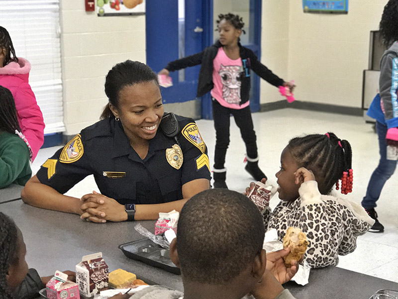 An officer laughs with children in a school cafeteria